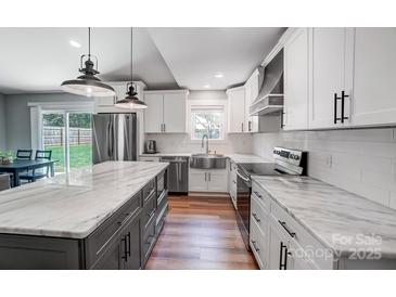 Modern kitchen with stainless steel appliances, white cabinets, and marble countertops at 3612 Cobbleridge Dr, Charlotte, NC 28215