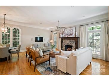 Bright living room featuring a stone fireplace, hardwood floors, and stylish furniture at 3819 Gleneagles Rd, Charlotte, NC 28210