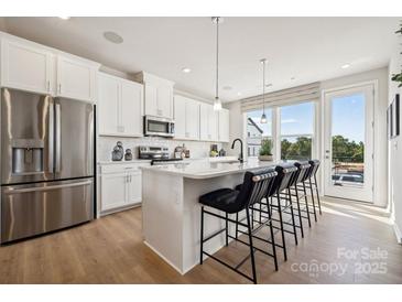 Bright kitchen featuring white cabinets, stainless steel appliances, and a large center island with bar seating at 5051 Westmead Ln, Charlotte, NC 28262