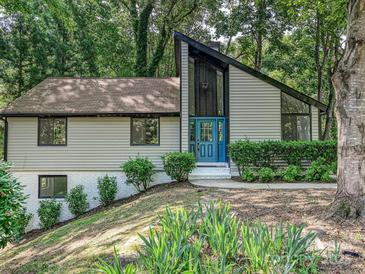 Charming home featuring a unique roofline, a blue front door, and mature landscaping at 6745 Thermal Rd, Charlotte, NC 28211