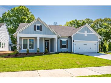 Charming one-story home with blue siding, well-manicured lawn, and attached two-car garage at 7185 Chamberlain Dr, Harrisburg, NC 28075