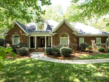 Traditional brick home with arched windows, manicured shrubs, and a walkway leading to a covered front entrance at 9101 Oak Bluff Ct, Marvin, NC 28173