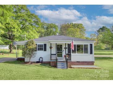 Charming home with white siding, black shutters, and well-maintained front lawn under a partly cloudy sky at 103 Moore Ave, Mount Holly, NC 28120