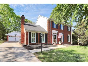 Charming brick two-story home with black shutters, manicured lawn and detached two-car garage at 200 Port Royal Dr, Matthews, NC 28105
