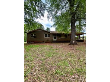 Single story home with a brick exterior and covered parking surrounded by mature trees in the front yard at 204 Long Creek Rd, Bessemer City, NC 28016