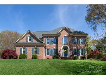 Stunning brick two-story home with manicured lawn and blue shutters on a sunny day at 3010 Lakewood Edge Dr, Charlotte, NC 28269