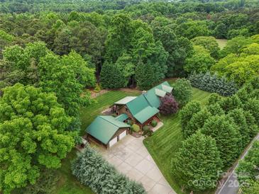 Stunning aerial view of a green-roofed log home nestled within a lush, dense forest at 10583 Earnhardt Lake Rd, Davidson, NC 28036