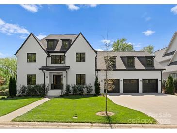 Elegant two-story home with a manicured lawn, black trim, and a spacious three-car garage at 1446 Townes Rd, Charlotte, NC 28209