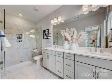Modern bathroom featuring a glass-enclosed shower with marble tile and dual sink vanity with white cabinetry at 5055 Westmead Ln, Charlotte, NC 28262