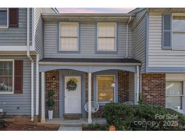 Charming two-story townhouse featuring a cozy front porch and decorative wreath on the front door at 7324 Pebblestone Dr # E, Charlotte, NC 28212