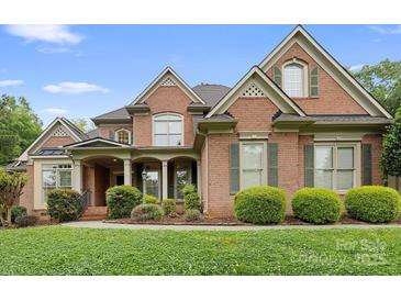 Charming brick home with manicured landscaping, symmetrical design, and inviting covered front porch at 7600 Brookmont Ln, Waxhaw, NC 28173