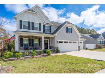 Charming two-story home with a stone-accented porch, three-car garage, and well-manicured lawn at 8419 Everwood Ave, Huntersville, NC 28078