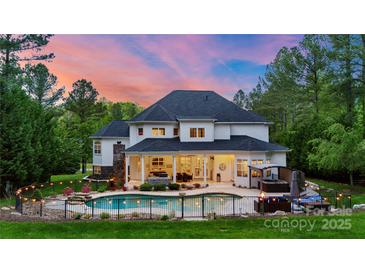 Stunning backyard oasis with a sparkling pool, manicured landscaping, and inviting outdoor living space with fence and string lights at 133 Crooked Branch Way, Troutman, NC 28166