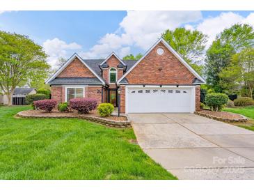 Charming brick home featuring a two-car garage, manicured lawn, and colorful landscaping at 2104 Planters Knoll Dr, Monroe, NC 28110