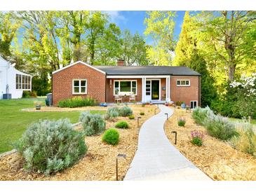 Charming brick home featuring a beautifully landscaped front yard with a stone walkway and lush greenery at 2121 Arnold Dr, Charlotte, NC 28205