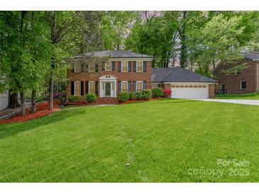 Charming two-story brick home with a well-manicured lawn and mature trees at 6634 Rocky Falls Rd, Charlotte, NC 28211