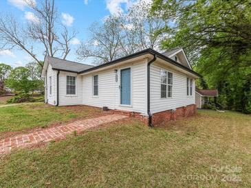 Charming home with a brick pathway leading to the light blue front door and white siding at 721 Broad St, Kannapolis, NC 28081