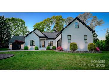 Charming white brick home with dark trim, landscaped yard and a well-manicured lawn at 8271 Camelia Ln, Denver, NC 28037