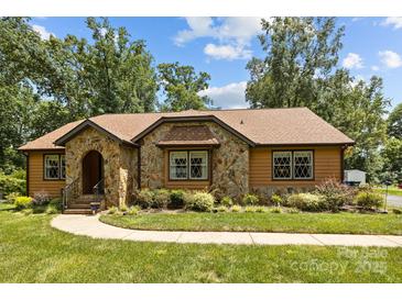Charming home featuring a stone facade, meticulously landscaped yard, and classic architectural details at 8835 Glencroft Rd, Mint Hill, NC 28227