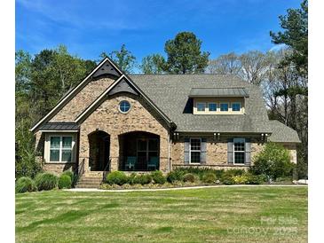 Charming brick home featuring a manicured lawn, arched porch, and classic architectural details on a sunny day at 15210 Pavilion Valley Cir, Huntersville, NC 28078