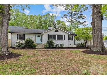 Charming single-story home with a light blue door, green trees, and a well-maintained front yard at 1601 Gambia St, Charlotte, NC 28208