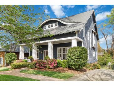 Charming home showcasing a meticulously landscaped front yard and inviting covered porch with classic columns at 1921 Brandon Cir, Charlotte, NC 28211
