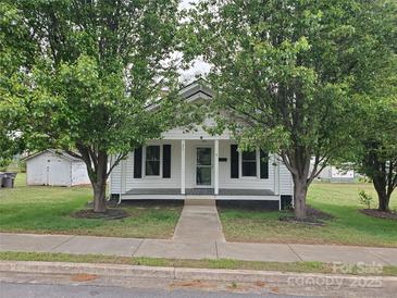 Charming single story home with white siding and a covered front porch, framed by mature trees at 301 E 11Th St, Kannapolis, NC 28083