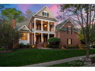 Stately two-story brick home featuring a welcoming front porch with elegant columns and manicured landscaping at 3301 Mcpherson St, Waxhaw, NC 28173