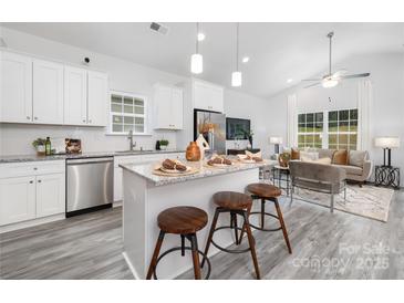 Bright kitchen features a large island with seating, stainless steel appliances, and an open layout to the living room at 5828 Patton St, Charlotte, NC 28269