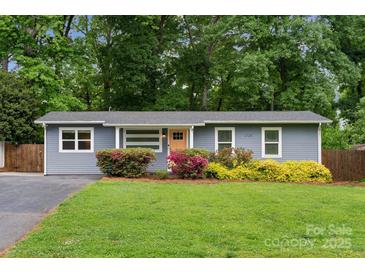 Charming single-story home with a well-manicured lawn, vibrant landscaping and a welcoming yellow door at 3725 Dunwoody Dr, Charlotte, NC 28215