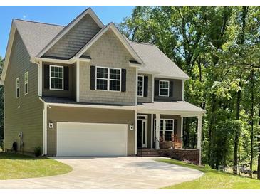 Two-story home with a large two-car garage, neutral color palette, and covered front porch with rocking chairs at 4476 River Rd, Stanfield, NC 28163
