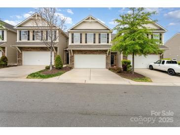 Charming townhome featuring stone accents, a two-car garage, and manicured landscaping at 832 Summerlake Dr, Fort Mill, SC 29715