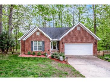 Charming single-story brick home with attached garage, manicured lawn, and mature trees providing shade at 1050 Emerson Dr, Mooresville, NC 28115