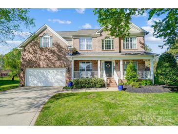Charming brick home featuring a welcoming front porch, well-manicured lawn, and attached garage at 15407 Saxon Trace Ct, Huntersville, NC 28078