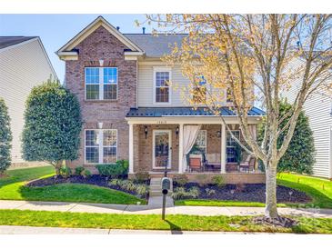Charming two-story brick home with a welcoming front porch and manicured landscaping at 15613 Troubadour Ln, Huntersville, NC 28078