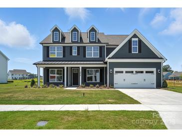 Charming two-story home featuring a well-manicured lawn, a two-car garage, and classic architectural details at 3214 Mcharney Dr # 34, Harrisburg, NC 28075