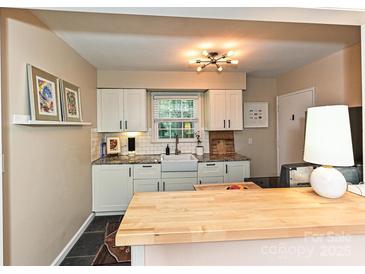 Modern kitchen features white cabinets, granite countertops, and undermount sink at 557 Wakefield Dr # A, Charlotte, NC 28209