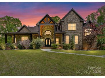 Stunning two-story brick home with a manicured lawn and inviting entrance at dusk at 633 Elmhurst Dr, Fort Mill, SC 29715