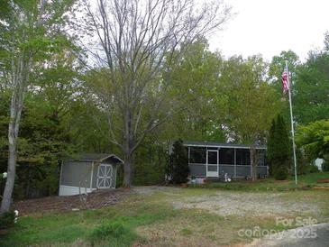 Charming home with a screened in porch, storage shed, and landscaped yard on a treed lot at 124 Hummingbird Cir, New London, NC 28127