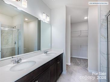 Bright bathroom featuring double sinks, a large mirror, and a walk-in shower with marble tile surround at 2579 Ruby Dixon Crossing Dr # 12, Gastonia, NC 28056
