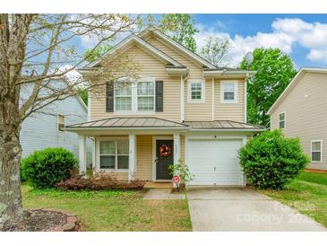 Charming two-story home featuring tan siding, black shutters, a cozy front porch, and a one-car garage at 523 Tribune Dr, Charlotte, NC 28214