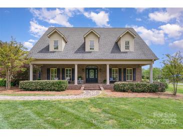 Charming brick home with a welcoming front porch, manicured lawn, and mature landscaping at 6419 Gilead Rd, Huntersville, NC 28078