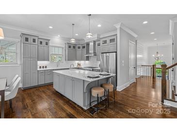 Bright kitchen features gray cabinetry, center island with seating, stainless steel appliances, and hardwood flooring at 911 Naples Dr, Davidson, NC 28036