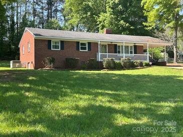 Charming, red brick, single-story home with well-maintained landscaping and a covered carport at 1014 Stuart Dr, Wadesboro, NC 28170