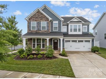 Charming two-story home with stone and siding facade, attached garage, and manicured front lawn at 12710 Es Draper Dr, Huntersville, NC 28078