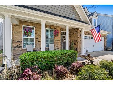 Charming brick home featuring a welcoming front porch with white columns and beautiful landscaping at 152 Blossom Ridge Dr, Mooresville, NC 28117