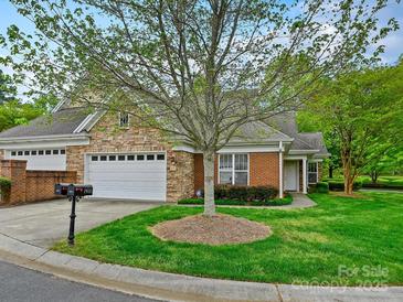 Traditional home featuring brick and stone exterior, large driveway, mature trees and well-kept lawn at 1910 Mezzo Ct, Matthews, NC 28105