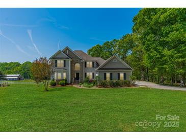 Beautiful two story home with a lush green lawn, mature trees, and architectural details at 228 Red Dog Dr, Mooresville, NC 28115