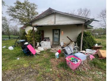 Shows a dilapidated house with peeling paint, debris, and overgrown vegetation in disrepair and in need of renovation at 2702 W Stage Coach Trl, Shelby, NC 28150