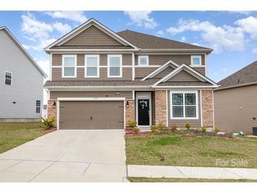 Well-maintained two-story home with brown siding, stone accents, a two-car garage and nice landscaping at 9727 White Chapel Nw Dr, Concord, NC 28027